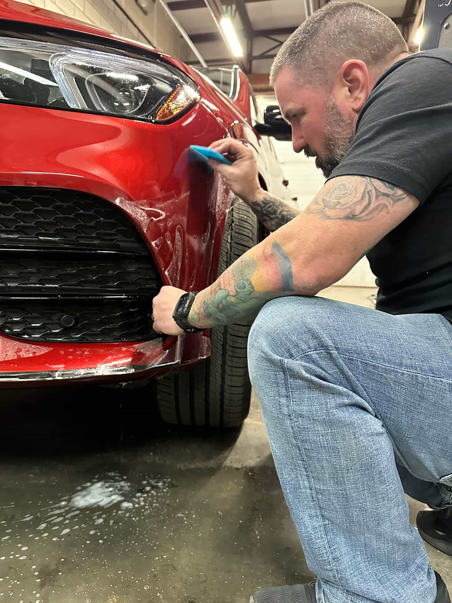 KCL Creations technician applying paint protection film to a vehicle in the shop